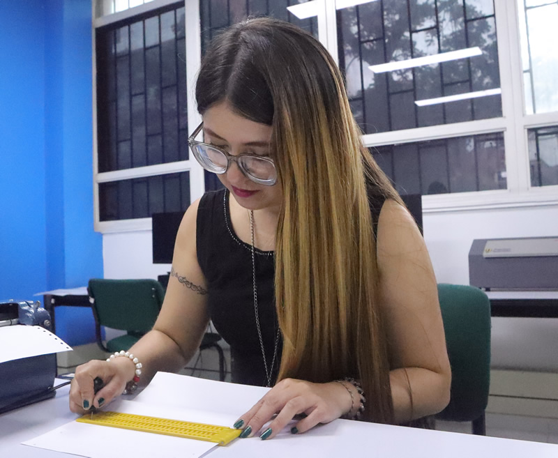 Fotografía de una estudiante escribiendo en Braille.